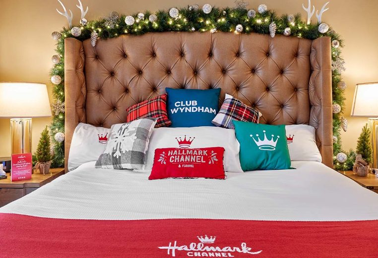A bed covered in Club Wyndham holiday pillows inside Hallmark Channel Countdown to Christmas Holiday suite at Club Wyndham Resort at Avon. 