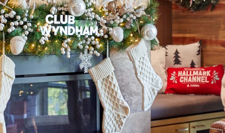 A fireplace decorated with Club Wyndham holiday garland and stockings inside a Hallmark Channel Countdown to Christmas Holiday suite at Club Wyndham Resort at Avon. 