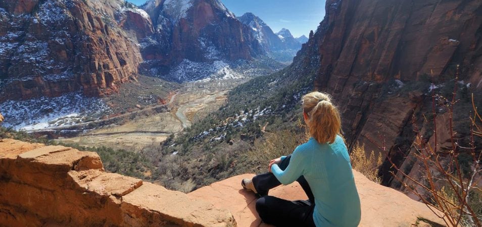 A woman sits on a rock overlooking Zion National Park in St. George, Utah